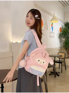 Adorable sac à dos mouton rose avec nœud et pendentif en peluche, style kawaii doux.