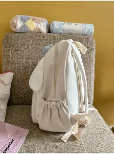 Vue détaillée du joli sac à dos en peluche blanche aux longues oreilles, tissu doux et fin.
