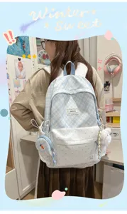 Détail de sac à dos à carreaux avec pois bleus, pendentif en peluche et mini porte-monnaie.