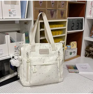 Detailansicht der weißen Canvas-Tragetasche mit Sternenmuster, Reißverschlüssen und Anhänger.