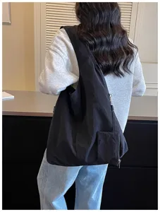 Vista dettagliata della borsa a tracolla casual in nylon nero con un piccolo marsupio.