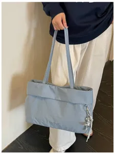 Vista dettagliata di una borsa tote plissettata azzurra con spallacci e ciondolo.