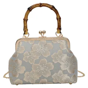 Vintage floral brocade handbag detail featuring a unique bamboo handle and gold frame.