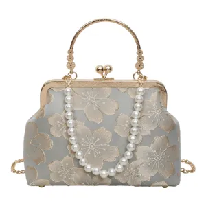 Close-up detail of the vintage kiss-lock handbag, featuring gold metal frame and pearl strap.