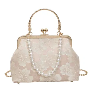 Vintage floral embroidered kiss lock handbag with pearl handle and metal frame for women.