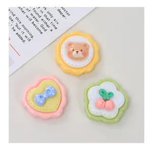 Primo piano di simpatici cabochon in resina con orsetto, fiocco e ciliegia per lavori fai-da-te.