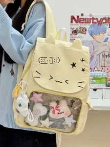 Dettaglio zaino ita orecchie di gatto, finestra trasparente, morbidi ciondoli di peluche, giallo.