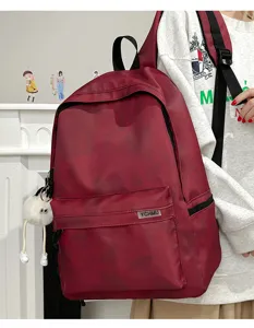 Casual tie-dye college backpack detail view featuring front pocket and cute plush pendant.