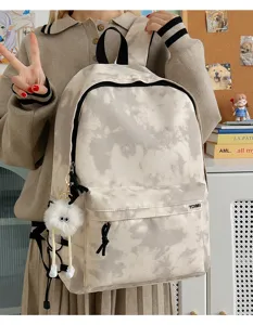 Tie-dye backpack detail view, large capacity school bag with cute plush pendant for students.