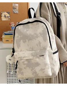 Detail view of the stylish tie-dye casual backpack with front pocket and cute fuzzy pendant.