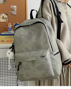 Detail shot of the tie-dye canvas backpack featuring front pocket and plush pendant.