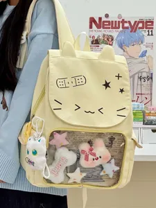 Primo piano dello zaino giallo con finestra trasparente, emoticon di gatto e ciondoli peluche.