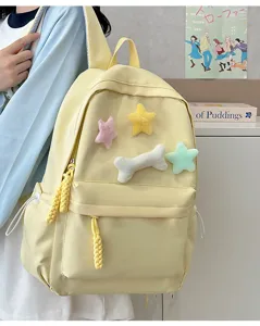 Detailed closeup view of the cute yellow student backpack featuring plush star and bone charms.