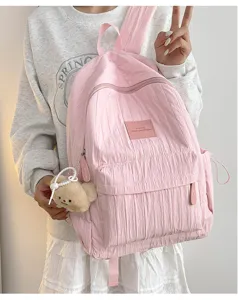 Detailed view of a lightweight pink solid color school backpack featuring a cute plush bear pendant.