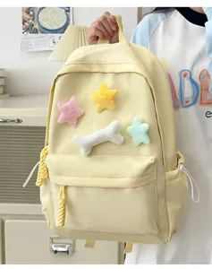 Detail view of cute yellow student canvas backpack featuring adorable plush star and bone charms.