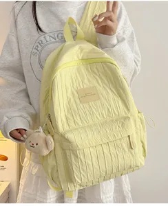 Close-up of lightweight pleated yellow school backpack with cute bear pendant and front pocket.