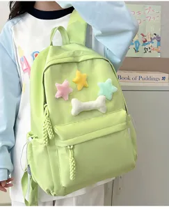 Cute pastel green student backpack with plush star and bone charms for school daily wear.