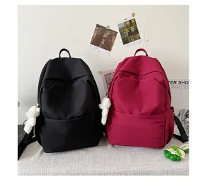 Casual solid color large capacity backpack detail view featuring multiple pockets and cute pendant.