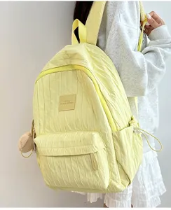 Detailed view of the lightweight yellow pleated backpack with front patch and charm.