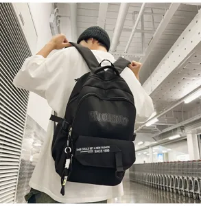 Detail shot of the black canvas backpack with front ribbon slogan and large storage capacity.