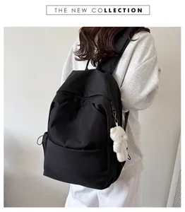 Detailed view of casual black backpack with plush bear pendant and front zipper pocket.