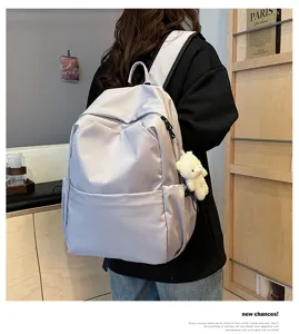 Detail view of a minimalist solid color large capacity backpack worn by a model comfortably.