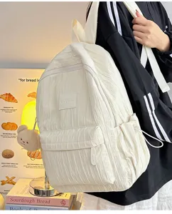 Detail view of lightweight white pleated backpack with cute bear pendant and pockets.