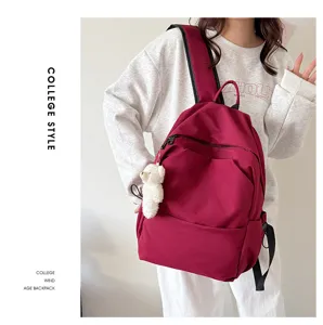 Casual solid color large capacity college style backpack with cute bear pendant for daily use.