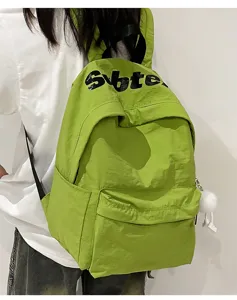 Dettaglio ravvicinato di uno zaino casual verde brillante con stampa a lettere e ciondolo.