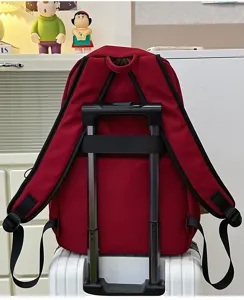 Detail view of solid red minimalist backpack featuring a convenient luggage trolley strap design.
