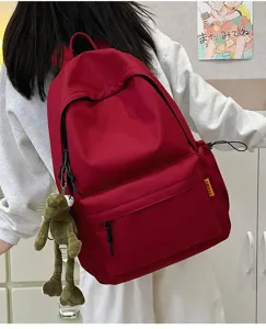 Detail view of the large capacity solid color school backpack with front pocket and cute frog charm.