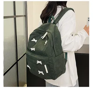 Green corduroy backpack detail view, featuring cute white bow accents and practical straps.