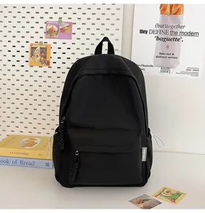 Detailed view of a minimalist black backpack with front zipper pocket and stylish woven pulls.