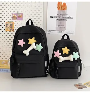 Black canvas student backpack set with cute plush star and bone charms for school.