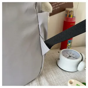 Close-up detail of grey backpack strap attachment showing durable stitching and web fabric.