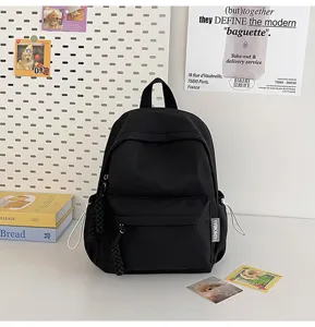 Minimalist black backpack detail featuring front zipper pocket and braided zipper pulls.