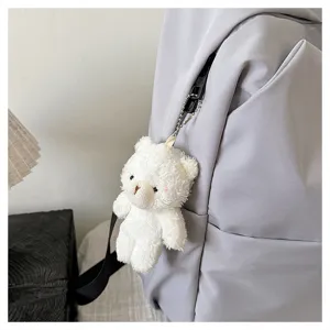 Detailed close-up view of a grey backpack zipper featuring a cute white plush bear pendant.