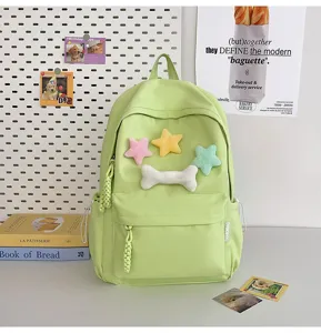 Detail view of light green student backpack featuring cute plush star and bone patches design.