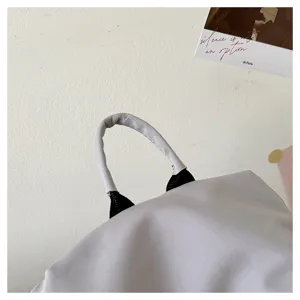Close-up detail of the grey backpack top handle showing durable fabric and solid stitching.