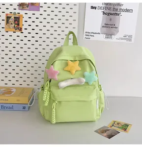 Green student mini backpack detail with cute plush star charms and front pocket design.