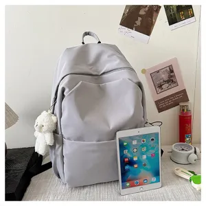 Detail view of the minimalist grey casual backpack, featuring a cute small bear plush pendant.