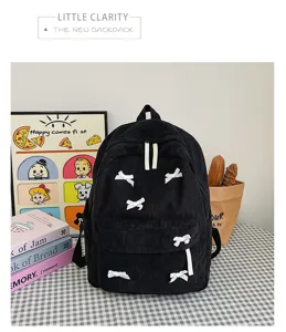 Black corduroy backpack detail featuring cute white bow accents and aesthetic lifestyle props.