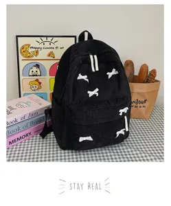 Detail shot of the black corduroy backpack decorated with sweet white bows in cozy setup.