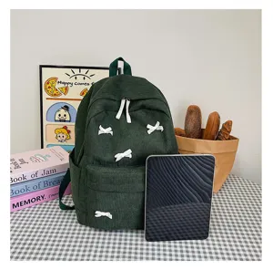 Green corduroy backpack detail view, featuring cute white bows, casual daily student bookbag.