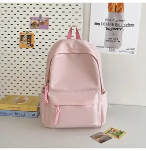 Pink minimalist casual school backpack with front pocket and charms for daily use.