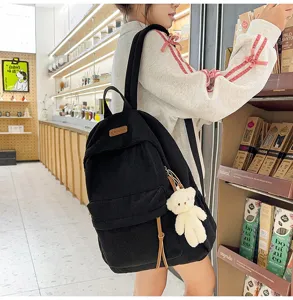 Black corduroy backpack with cute bear pendant, stylish school bag for students.