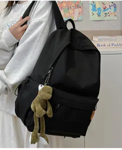 Close-up detail of the large capacity black backpack featuring a cute plush pendant design.