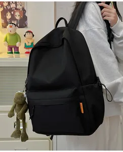 Minimalist solid color large capacity school backpack with cute frog pendant for students.