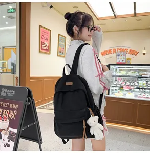 Black corduroy backpack for women, stylish school bag with cute bear pendant and large capacity.