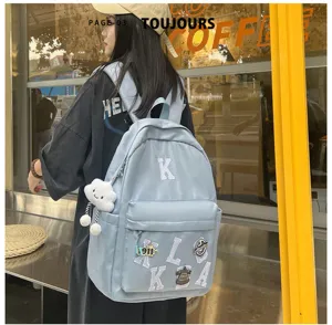 Detail shot of the light blue student backpack with letter patches and cute cloud pendant in cafe.